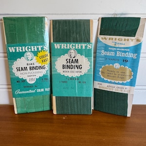 May include: Three packages of Wright's Seam Binding in shades of green. The packages have text that reads "Bias Seam Binding", "Seam Binding", and "Seam Binding". The packages are labeled with the color names Emerald, Jade, and Jungle Green.