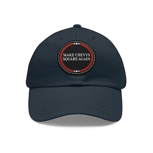 May include: A navy blue baseball cap with a curved peak. The cap has a circular patch with the text "MAKE CHEVYS SQUARE AGAIN" in white, encircled by red and white stripes and stars. A classic, adjustable hat.