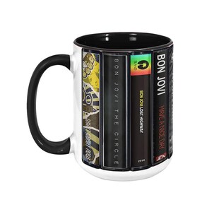 Pode incluir: Caneca de cer&acirc;mica branca com al&ccedil;a e interior pretos. A caneca apresenta capas de &aacute;lbuns do Bon Jovi, incluindo "Have a Nice Day", "Lost Highway" e "The Circle". A caneca &eacute; um item colecion&aacute;vel com tema musical.