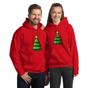 Könnte beinhalten: Zwei rote Kapuzenpullover. Jeder Kapuzenpullover hat ein pixeliges grünes Weihnachtsbaumdesign mit einem gelben Stern. Der Text "5000 COMMIT-MAS" ist auf dem Baum aufgedruckt. Die Kapuzenpullover werden von zwei Personen getragen.