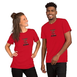 Peut inclure: Deux personnes portant des t-shirts rouges. Chaque chemise présente un petit dessin d'arbre de Noël avec le texte "Merry Christmas" au-dessus et du texte en dessous. Les personnes sourient.