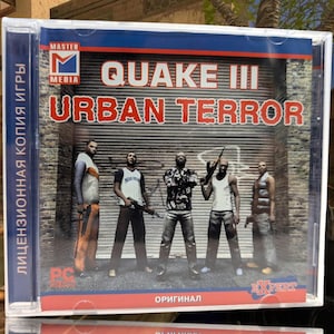 May include: A PC game case for Quake III Urban Terror. The cover features five men with weapons in front of a garage door. The game title is in red and white text. The case has a blue spine with Cyrillic text.