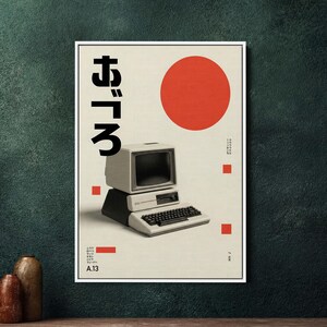 May include: A framed poster with a retro computer design, Japanese characters, and a red circle. The poster has a cream background and a white frame. The computer is depicted in shades of grey and black, evoking a vintage aesthetic.