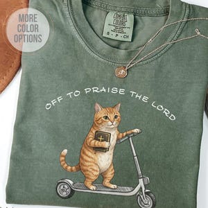 Funny Christian cat shirt with orange tabby riding scooter and holding Bible, Off To Praise The Lord graphic tee, cute religious cat lover gift shirt