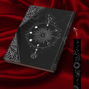 Peut inclure: Un journal noir avec un motif céleste. La couverture présente un soleil, des lunes, des étoiles et des constellations en blanc. La tranche et les coins ont des détails blancs ornés. Un marque-page assorti est inclus.