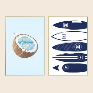 May include: Two framed art prints. The left print shows a halved coconut containing a miniature ocean scene with surfers and a beach umbrella. The right print displays five stylized surfboard illustrations in navy blue and white, each featuring a double C logo.