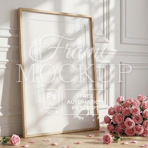 Op de afbeelding: Een houten fotolijst mockup leunend tegen een witte muur. Het frame is leeg, met de tekst "Frame Mockup" eroverheen. Roze rozen en bloemblaadjes liggen verspreid over de houten vloer. Bevat tekst: "Ps PSD", "+Free Automation PS Script" en "ISO A".