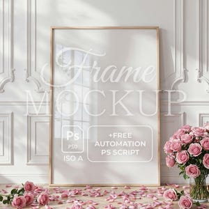 Op de afbeelding: Een grote, rechthoekige frame-mockup met een lichte houten afwerking leunt tegen een witte muur. Het frame heeft de tekst "Frame Mockup" en details over Photoshop-automatisering. Roze rozen en verspreide bloemblaadjes zorgen voor een bloemige touch.