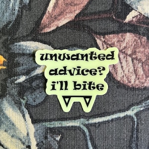 May include: A neon green sticker with the text "unwanted advice? i'll bite" in black, stylized font. The sticker has a unique shape with two downward-pointing triangles at the bottom.