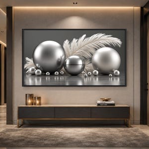 May include: A framed artwork with metallic spheres and white feathers on a grey background. The spheres are of different sizes, forming a modern, abstract design. The artwork hangs above a dark grey and wood-toned cabinet.