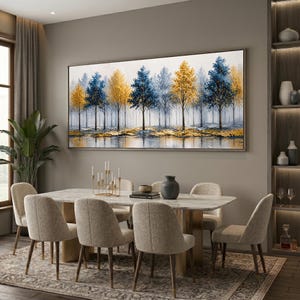 Op de afbeelding: Een groot rechthoekig wandkunstwerk met een olieverfschilderij van een boslandschap met afwisselend blauwe en gouden bomen. De scène toont een dicht bos met een reflecterend grondoppervlak, uitgevoerd in een textuurrijke, impressionistische stijl.