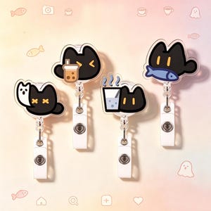Op de afbeelding: Vier intrekbare badgehouders met kattenmotief. Elk heeft een zwart kattenontwerp met verschillende accessoires: een bubble tea, een vis, een glas water en een kat met gekruiste ogen. De badgehouders hebben een transparant plastic ontwerp en witte clips.