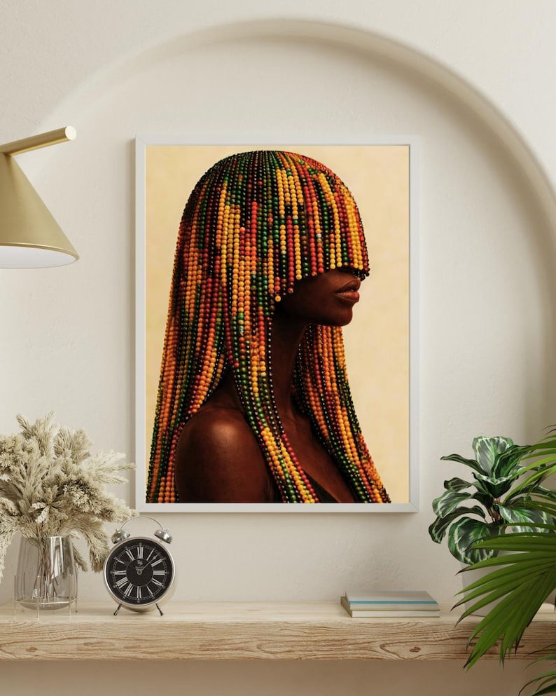 K&ouml;nnte beinhalten: Ein gerahmter Kunstdruck mit einem Seitenprofil einer Person mit dunkler Haut. Das Haar der Person ist mit farbigen Perlen in Gelb-, Orange-, Rot- und Gr&uuml;nt&ouml;nen gestaltet. Das Kunstwerk wird auf einem Regal mit einer Uhr und dekorativen Gegenst&auml;nden ausgestellt.