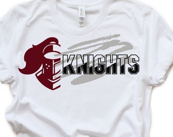 Può includere: Maglietta bianca con una grafica di un elmo da cavaliere color granata e la parola "KNIGHTS" in testo nero. La grafica è sovrapposta a un design di pennellate grigie.