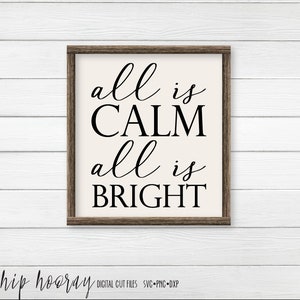May include: A framed sign with the text "all is CALM all is BRIGHT" in black cursive font on a cream background.