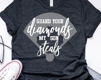 May include: A dark gray t-shirt with a white graphic design of a baseball diamond. The text on the graphic reads "Guard Your Diamonds My Son Steals".