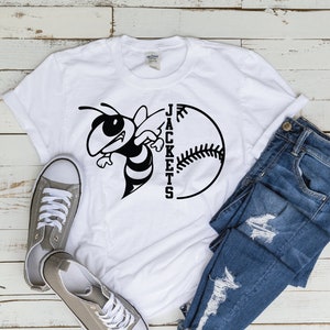 May include: White t-shirt with a black and white graphic of a bee and a baseball with the word "JACKETS" written vertically around the baseball.
