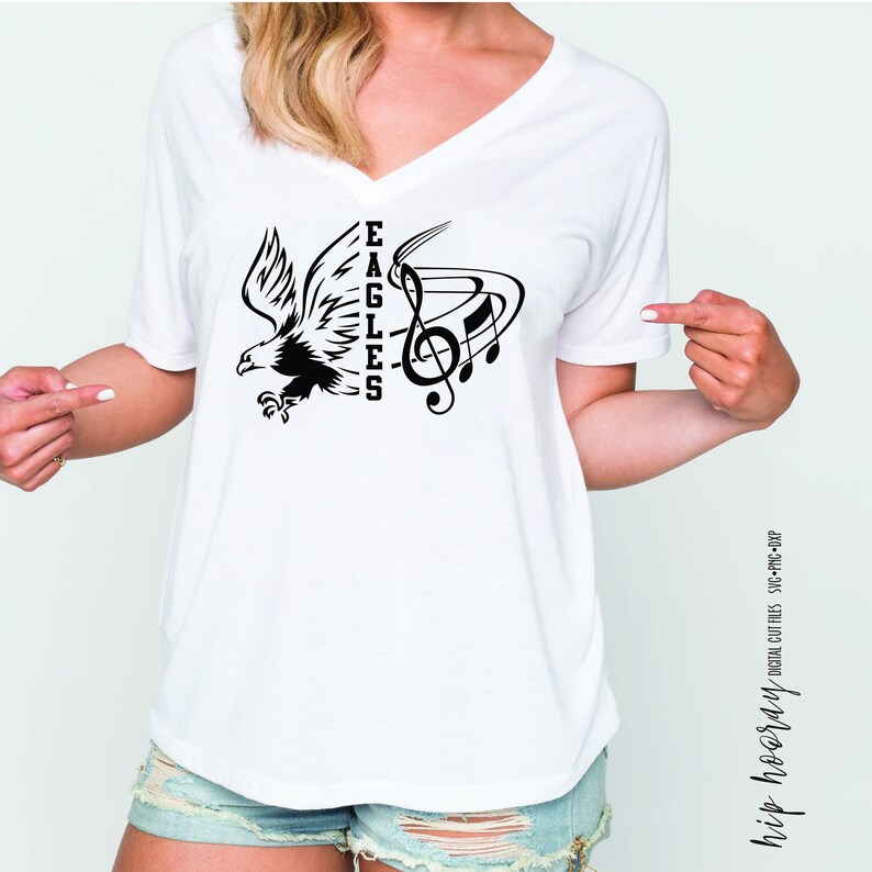 May include: White t-shirt with a black design of an eagle and musical notes. The text "EAGLES" is vertically oriented on the left side of the design.