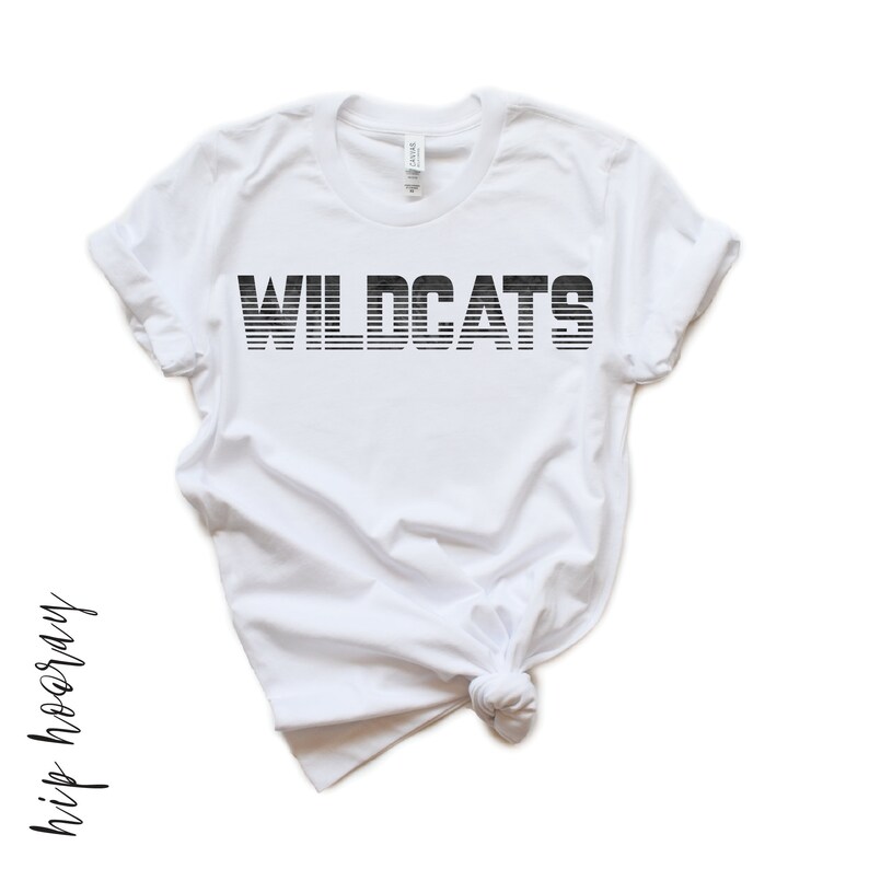 May include: White t-shirt with black text that reads "WILDCATS" in a striped font.