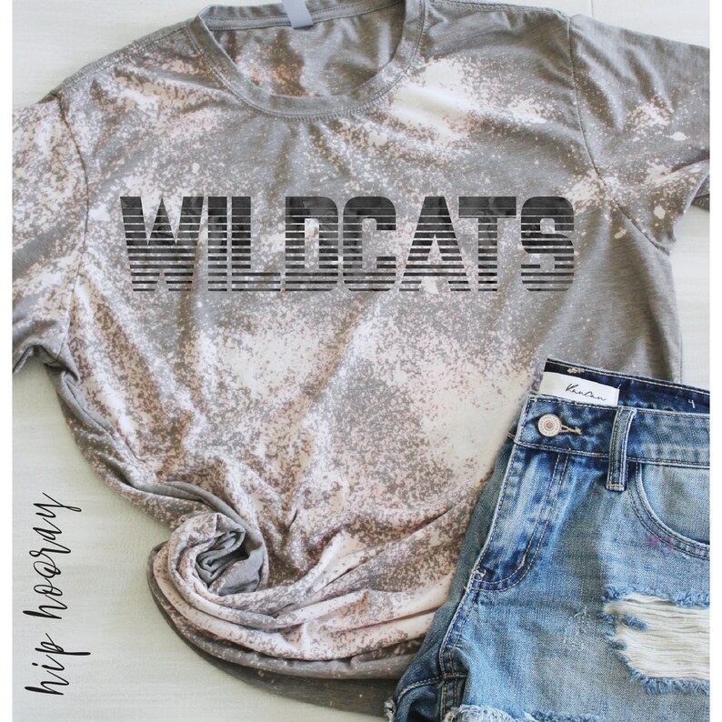 May include: A gray t-shirt with a bleach-splattered design. The shirt has the word "WILDCATS" printed in black across the front.