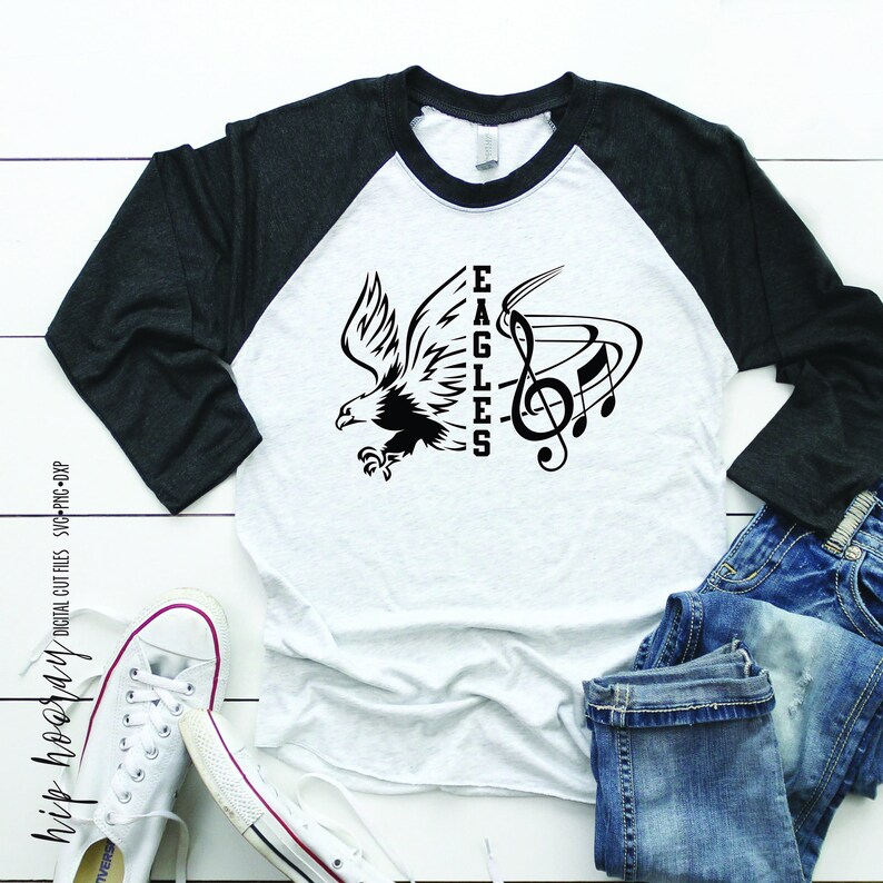 May include: A white and black baseball t-shirt with a black eagle design and the word "EAGLES" vertically down the side. A treble clef and musical notes are on the right side of the design.