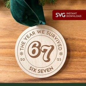 May include: A round wooden ornament with the text "THE YEAR WE SURVIVED 67" and "SIX SEVEN" in a brown font. The ornament is attached to a green velvet ribbon. The text "SVG INSTANT DOWNLOAD" is in the upper right corner.
