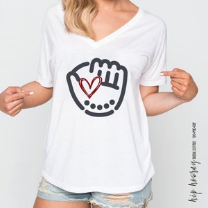 K&ouml;nnte beinhalten: Wei&szlig;es T-Shirt mit V-Ausschnitt und einem schwarzen und roten Grafikdruck eines Baseballhandschuhs mit einem Herzen darin. Die Grafik ist im einfachen Strichzeichnungsstil gehalten.