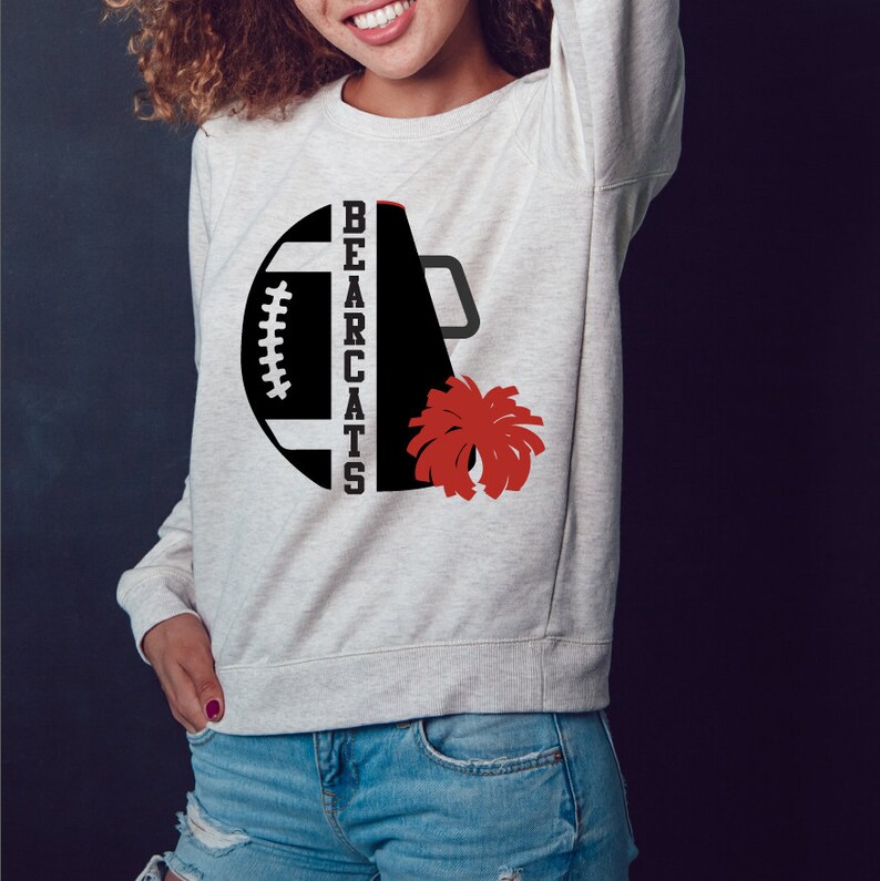 Op de afbeelding: Een wit sweatshirt met een zwart en rood ontwerp. Het ontwerp bevat een voetbal, een megafoon en de woorden "BEARCATS".