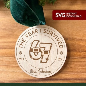 May include: A wooden Christmas ornament with the text "THE YEAR I SURVIVED" and the number "67" in a Santa-themed design. The ornament includes the name "Mrs. Johnson" and the years "20" and "25". A green velvet ribbon is attached.