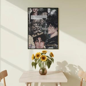 May include: A framed poster with a collage of images and text, including the words "Power" and "Kai Azer." The poster is displayed above a small table with a vase of sunflowers. The room has a neutral color palette.