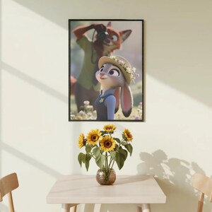 Może przedstawiać: Oprawiony wydruk z postaciami Judy Hopps i Nickiem Wilde z filmu Zwierzogr&oacute;d. Wisi nad stołem z wazonem słonecznik&oacute;w. St&oacute;ł jest otoczony dwoma drewnianymi krzesłami. Pok&oacute;j ma neutralną kolorystykę.