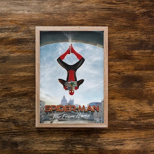 May include: Framed print featuring Spider-Man in a red and black suit, hanging upside down. The image includes the text "SPIDER-MAN Far From Home" and a cityscape background. The frame is a light brown color.