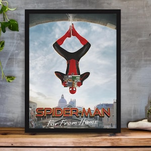 May include: Framed poster featuring Spider-Man in a red and black suit, hanging upside down. The poster has the title "Spider-Man: Far From Home" with a cityscape background and a blue sky. The poster is in a black frame.