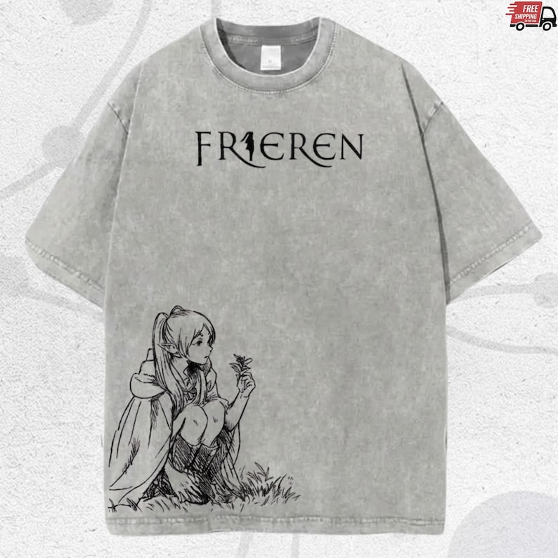 Puede incluir: Camiseta gris con la palabra "FRIEREN" en letras negras. Una ilustraci&oacute;n en blanco y negro de un personaje sosteniendo una flor est&aacute; en la parte inferior izquierda. La camiseta tiene un aspecto vintage.