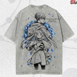 Puede incluir: Camiseta gris con una ilustraci&oacute;n de estilo anime de dos figuras y flores azules. La parte trasera de la camiseta incluye la cita: "S&oacute;lo avanzando aprendemos a entender la p&eacute;rdida."
