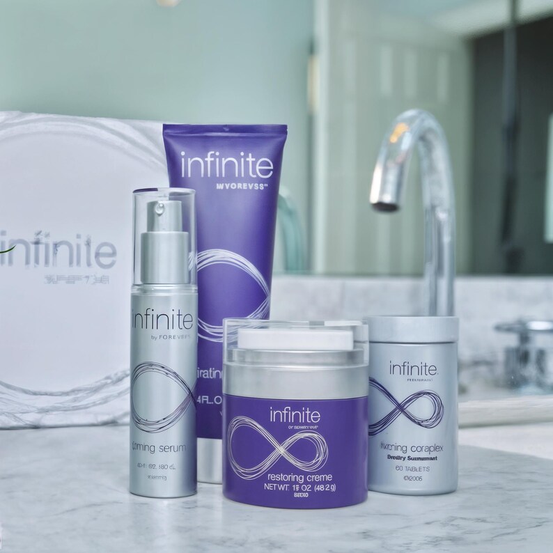May include: A collection of skincare products, including a serum, cream, and supplement, with the "infinite" logo. The products are in silver and purple packaging. The cream jar is labeled "restoring creme" with a net weight of 1.8 oz (48.2 g).