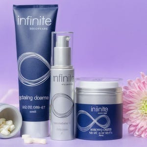 May include: A collection of skincare products, including a tube, a pump bottle, and a jar, all with the "infinite" logo. The products are in shades of blue and silver, with a white infinity symbol design. A container of pills and a pink flower are also present.
