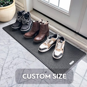 May include: A black, diamond-patterned doormat with the text "CUSTOM SIZE" displayed. Various pairs of shoes and boots are arranged on the mat, including black lace-up boots, brown heeled boots, and sneakers.