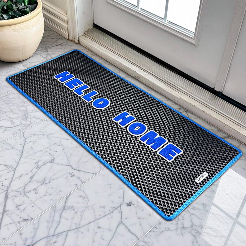 May include: A rectangular doormat with a black mesh pattern and a blue border. The words "HELLO HOME" are printed in bold blue letters. The mat is on a marble tiled floor near a white door.