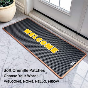 May include: A rectangular black doormat with a copper-coloured border and the word "WELCOME" in yellow block letters. The mat is made of soft chenille patches. The text "Soft Chenille Patches" and "Choose Your Word: WELCOME, HOME, HELLO, MEOW" are also visible.