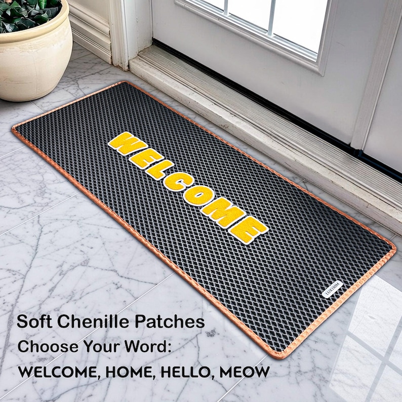 May include: A rectangular black doormat with a copper-coloured border and the word "WELCOME" in yellow block letters. The mat is made of soft chenille patches. The text "Soft Chenille Patches" and "Choose Your Word: WELCOME, HOME, HELLO, MEOW" are also visible.