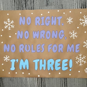 Puede incluir: Un letrero de papel marr&oacute;n con el texto "NO RIGHT, NO WRONG, NO RULES FOR ME I'M THREE!" en letras azules y moradas. Copos de nieve y puntos blancos rodean el texto.