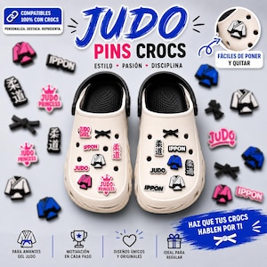 Könnte beinhalten: Ein Paar cremefarbene Clogs, verziert mit verschiedenen Judo-Schuhanhängern. Die Anhänger zeigen Miniatur-Judogi-Anzüge in Weiß und Blau, schwarze Gürtel, das Wort IPPON, das Wort JUDO sowie den rosa Schriftzug JUDO PRINCESS mit einer Krone.