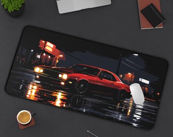 May include: A black rectangular desk mat featuring a red classic car illustration. The car is depicted in a nighttime street scene with reflections of lights on the wet pavement. A white mouse is on the right side of the mat.