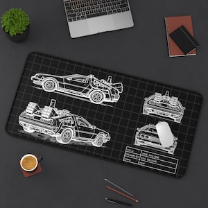 May include: Black mousepad featuring white line drawings of the DeLorean time machine from the movie Back to the Future. The design includes multiple views of the car and a blueprint-style title block. A computer mouse and keyboard are visible.