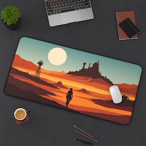 May include: A rectangular desk mat featuring a desert landscape design with a windmill, structures, and a person walking. The color palette includes shades of orange, brown, and blue. A white computer mouse is on the mat.