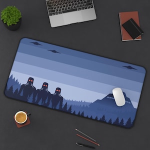 May include: A rectangular mouse pad featuring a blue landscape design with silhouettes of trees, figures with red eyes, and flying saucers. A white computer mouse is on the right side of the pad.