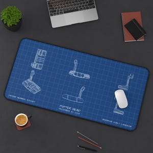 Peut inclure: Tapis de bureau bleu avec un plan de conception de tête de putter. Le design comprend plusieurs vues de la tête de putter, avec le texte "PUTTER HEAD DECEMBER 10, 2008" et "INVENTOR: DON T. CAMERON". Une souris et un clavier d'ordinateur sont également visibles.