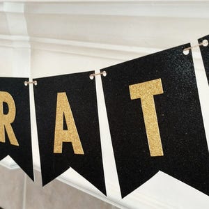 Pode incluir: Faixa de glitter preto e dourado com a palavra "CONGRATS" em letras douradas.