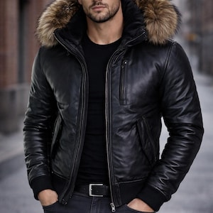 Puede incluir: Chaqueta de cuero negra con capucha ribeteada de piel. La chaqueta tiene cierre de cremallera, bolsillos y puños de canalé. La persona lleva una camisa negra y vaqueros oscuros. Una prenda de abrigo elegante.